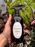 Black 500 ml Botanica & Co Foliage Tonic spray bottle held in front of foliage